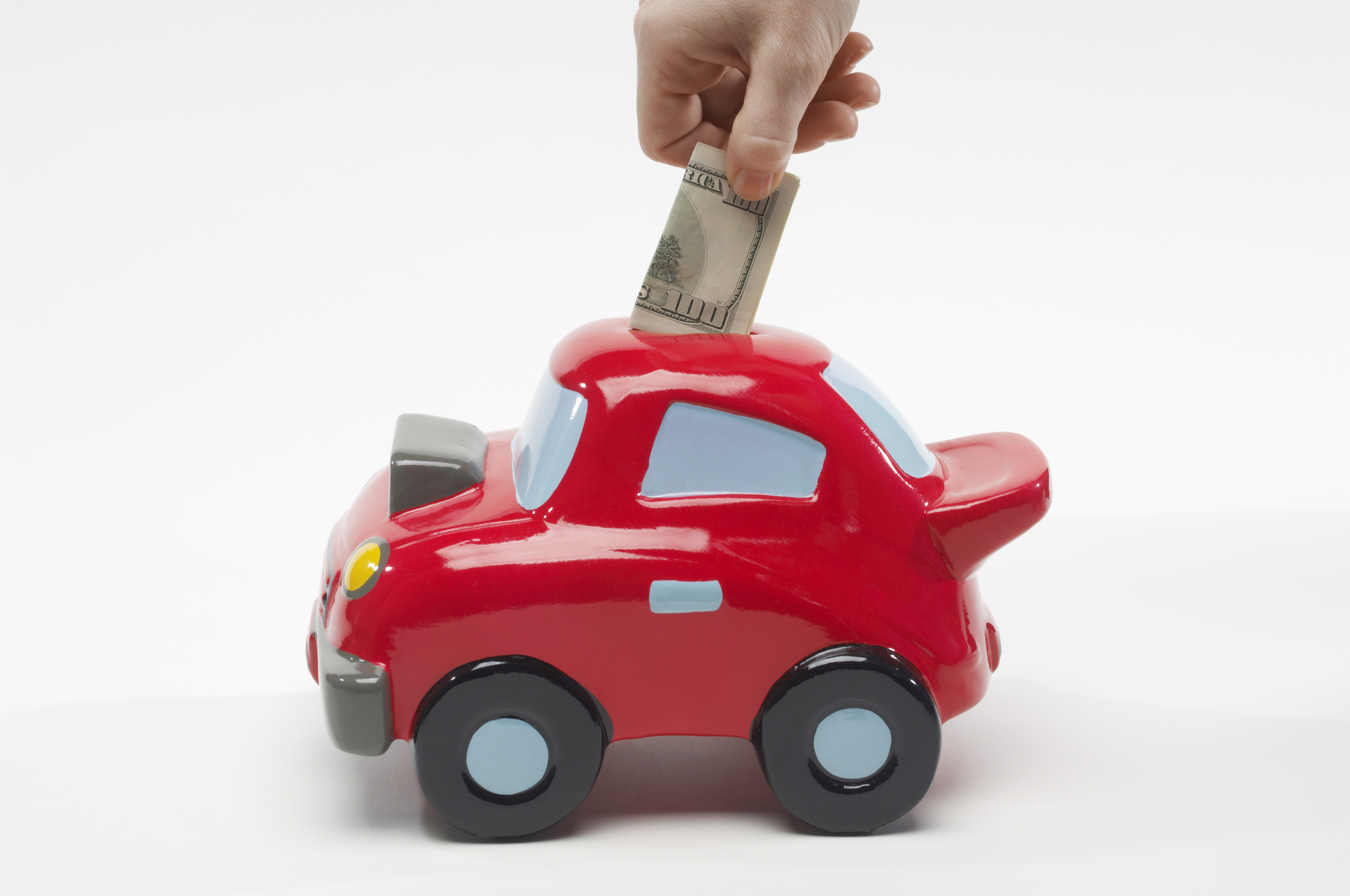 Hand Putting Money in Car Shaped Piggy Bank